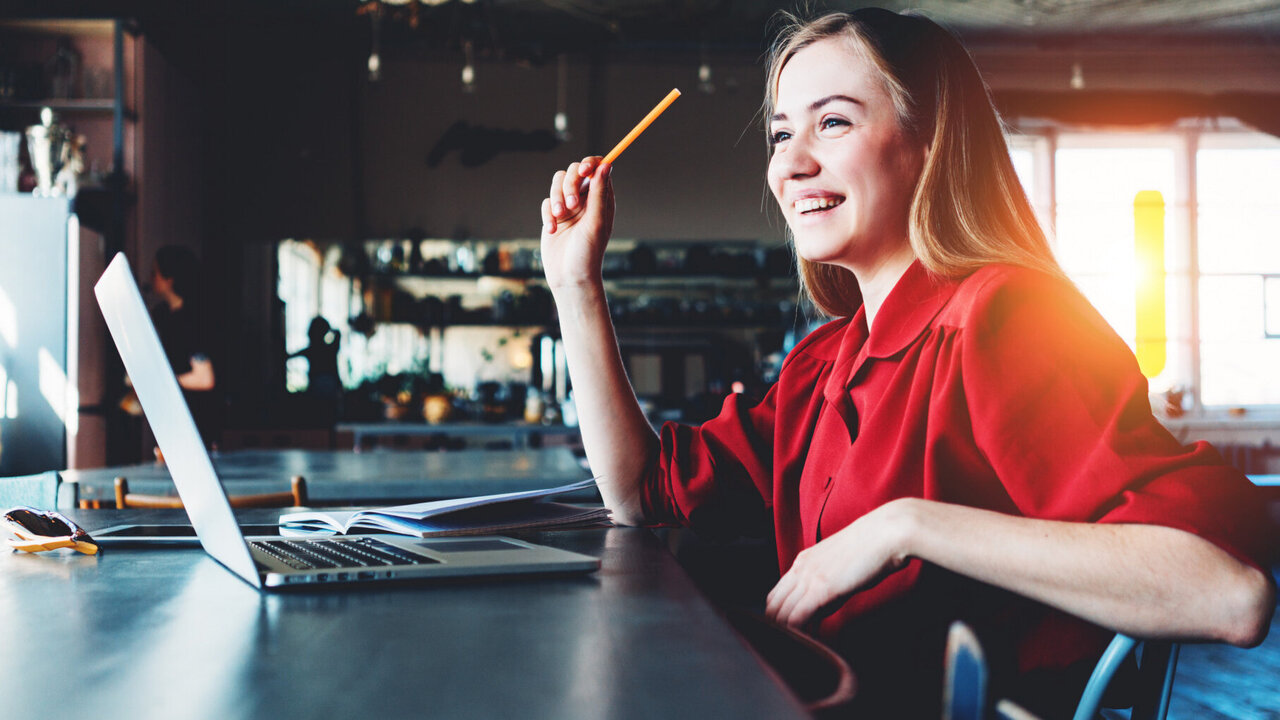 Woman with pen in hand in front of a laptop