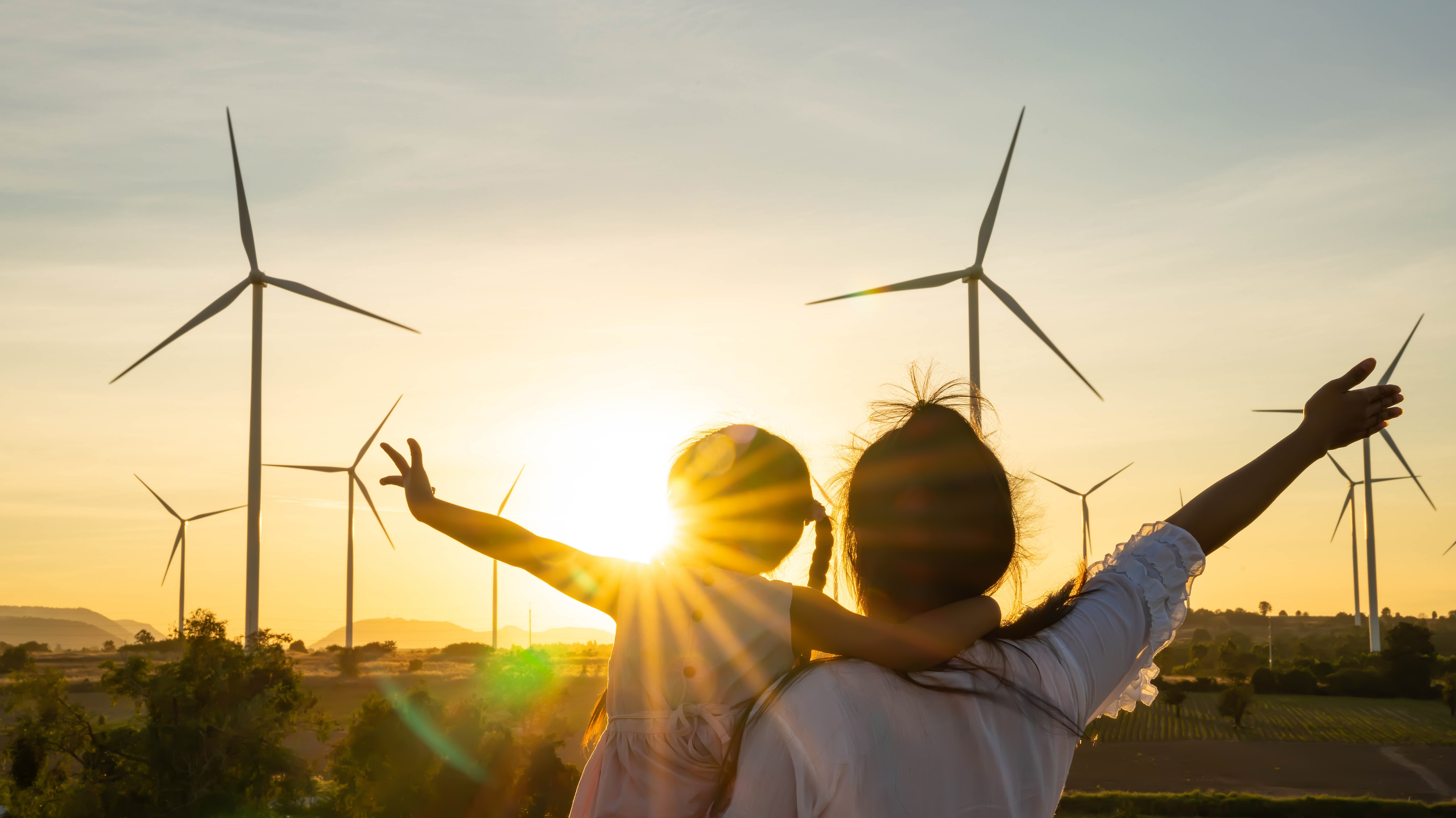 Securepoint setzt in vielen Bereichen auf erneuerbare Energien. Personen vor mehreren Windkraftanlagen.