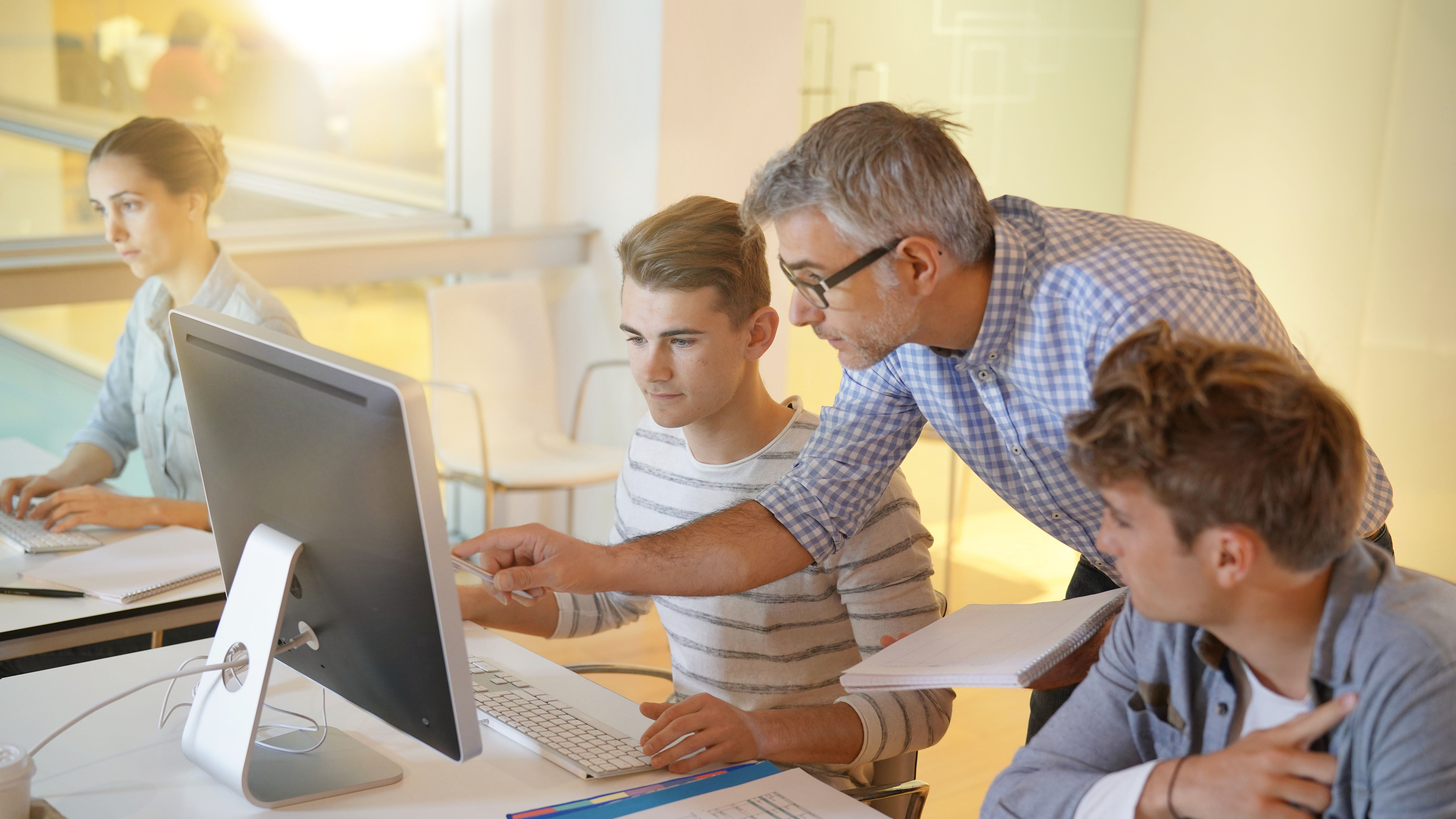 Die Schulen sicher digitalisieren mit Produkten von Securepoint. Lehrer erklärt Schülern den Umgang mit Computern.