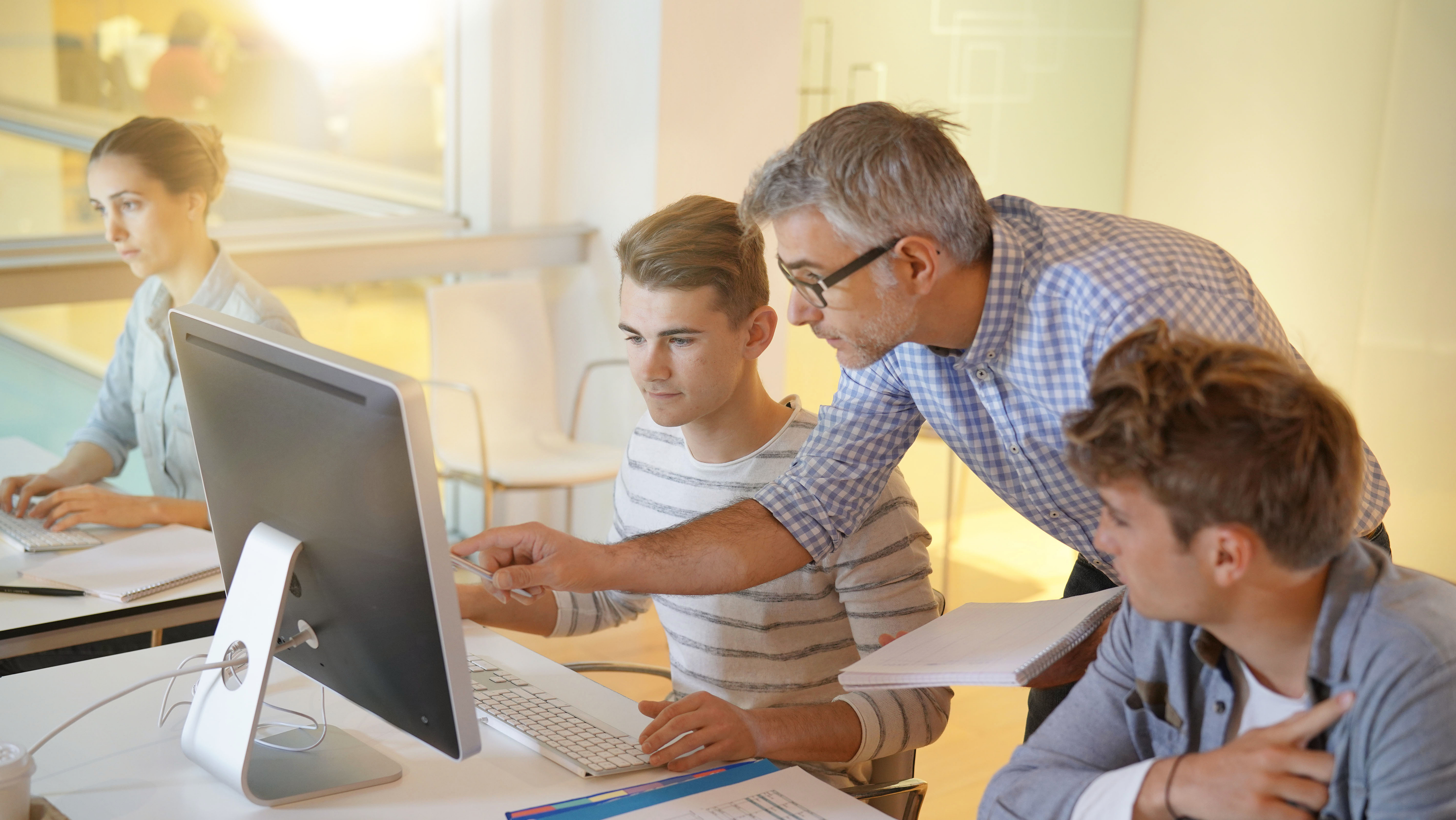 Die Schulen sicher digitalisieren mit Produkten von Securepoint. Lehrer erklärt Schülern den Umgang mit Computern.