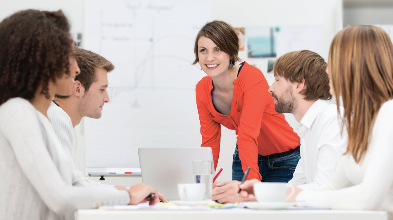 Woman with red top in a meeting with people dressed in white