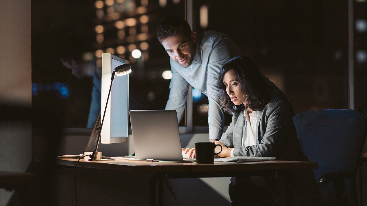 Zwei Personen sitzen abends gemeinsam am Computer Zwei Personen sitzen abends gemeinsam am Computer