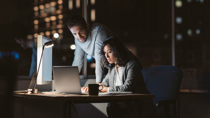 Zwei Menschen sitzen abends gemeinsam am Computer