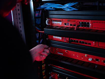 Ein Techniker schraubt eine Securepoint UTM-Firewall in ein Racksystem