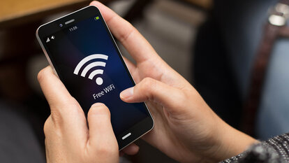 Gesicherte WLAN-Gastzugänge in Behörden und Ämtern. Smartphone mit großem WLAN-Symbol im Display.