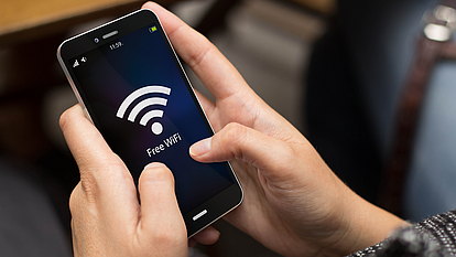 Gesicherte WLAN-Gastzugänge in Behörden und Ämtern. Smartphone mit großem WLAN-Symbol im Display.