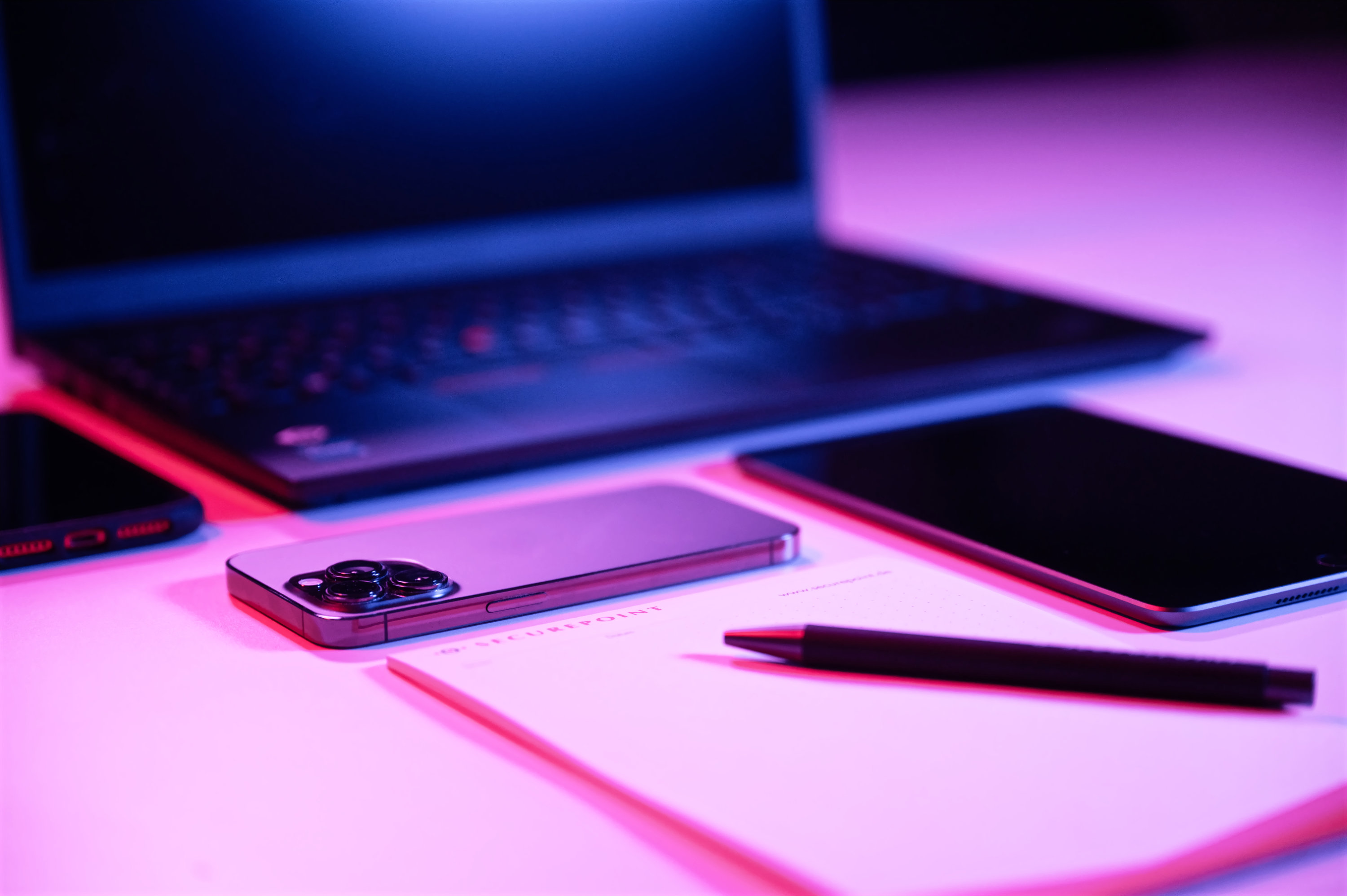 Laptop, Smartphone, Notizblock und Stift auf einem Schreibtisch