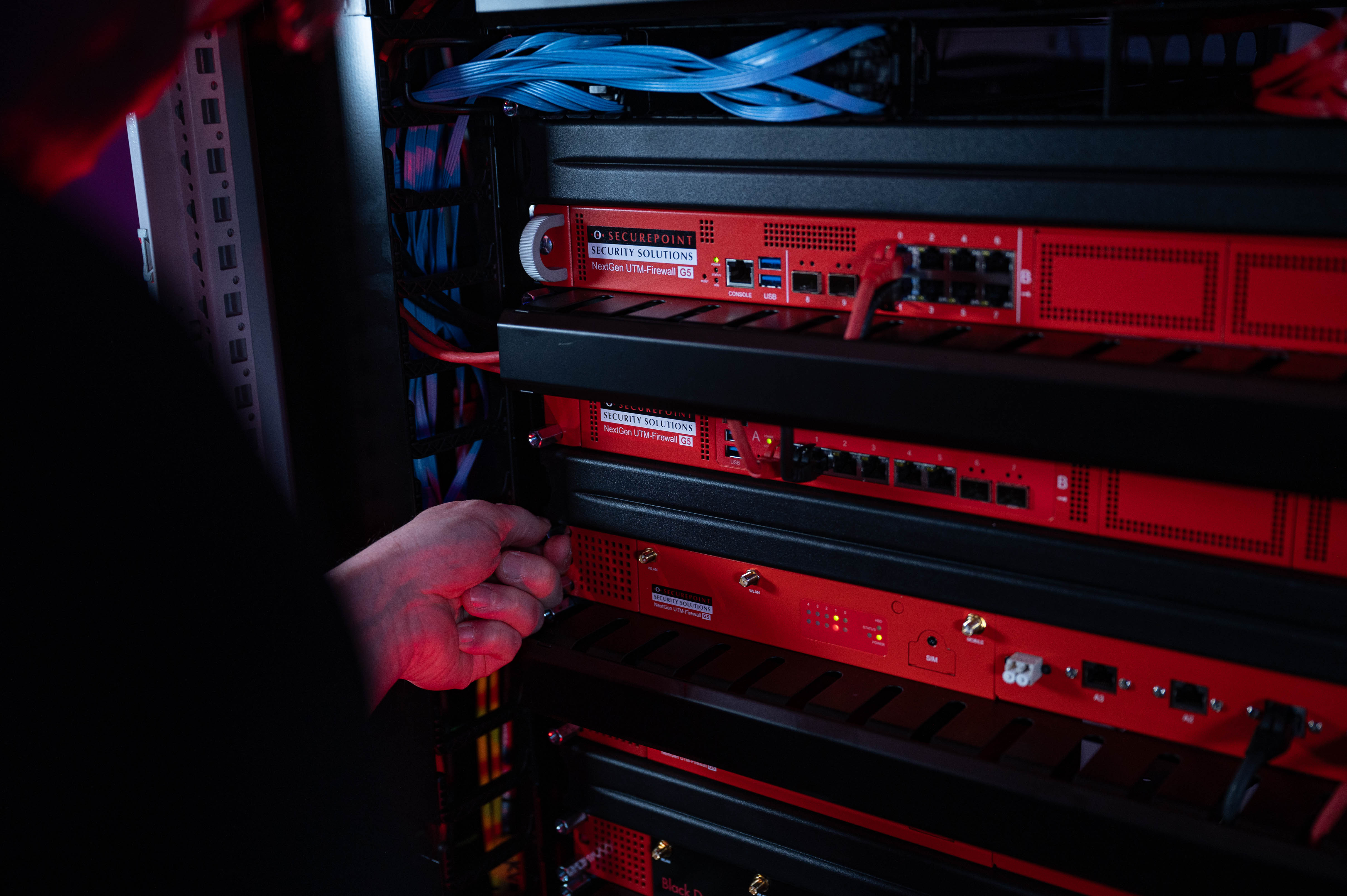 Ein Techniker schraubt eine Securepoint UTM-Firewall in ein Racksystem