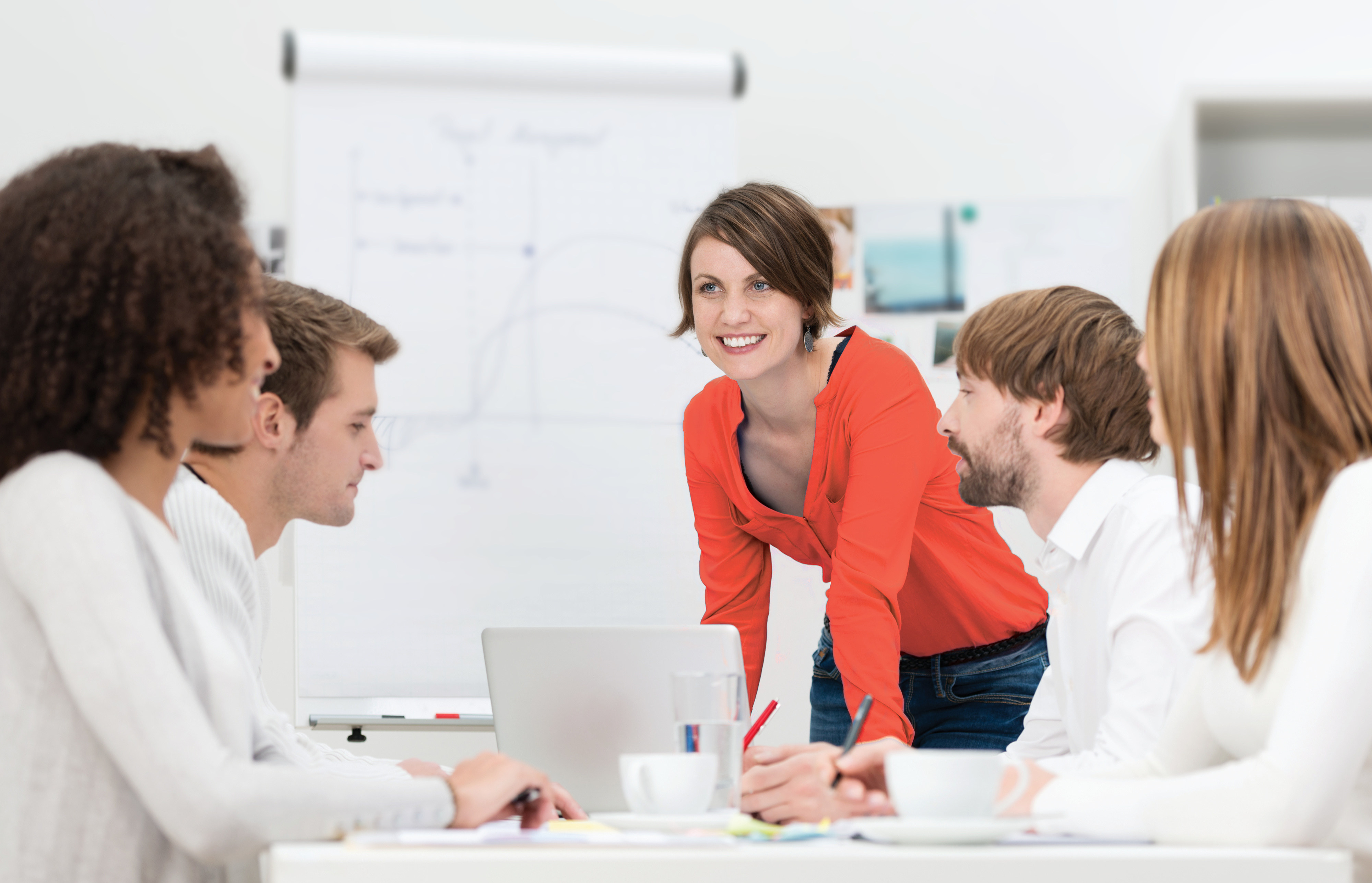 Frau mit roten Oberteil im Meeting mit weiß gekleideten Personen.