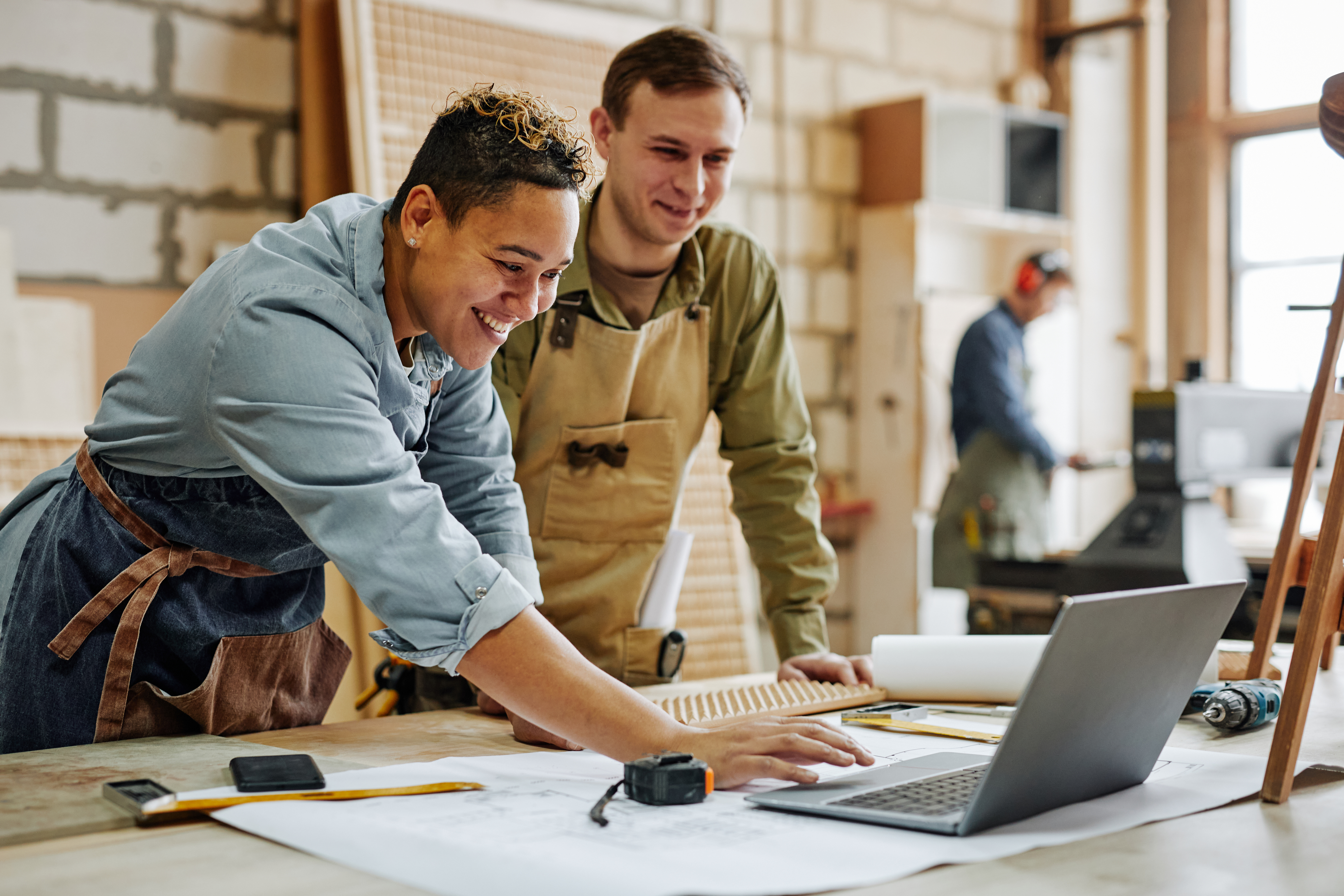 IT-Sicherheit für Handwerksbetriebe Zwei Handwerker kontrollieren Pläne auf einem Laptop.