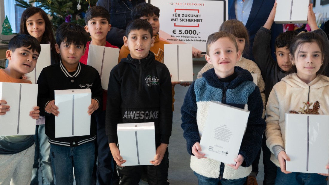 Spendenübergabe an den Förderverein der Hermann-Löns-Schule Kinder mit ihren gespendeten iPads und dexm Geschäftsführer von Securepoint mit einem 5000 Euro Scheck.