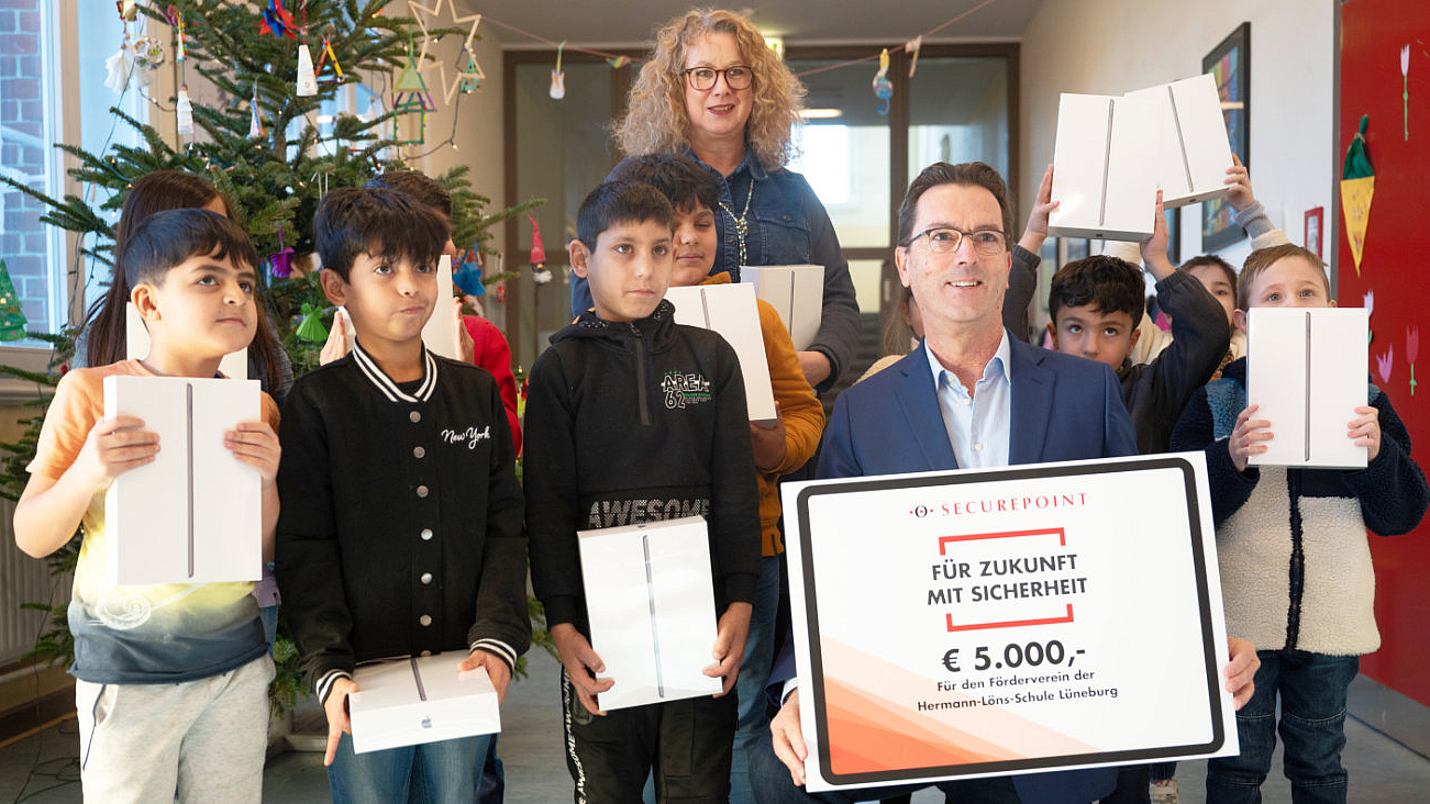 Donation handover to the Hermann-Löns-Schule booster club Children with their donated iPads and the CEO of Securepoint with a 5000 Euro cheque.